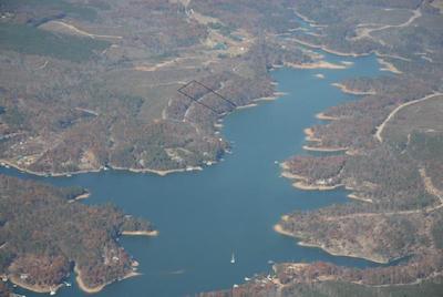 Helicopter view of a lake surrounded by trees with a plot of land outlined with a box