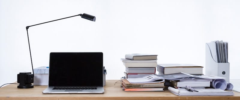 Desk with laptop, lamp, papers, books