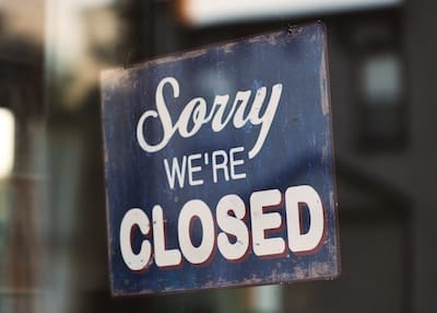 Sign on shop door with words "Sorry, we're closed"