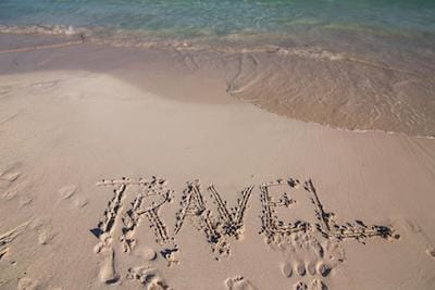 Sandy beach with the word "Travel" written in the sand