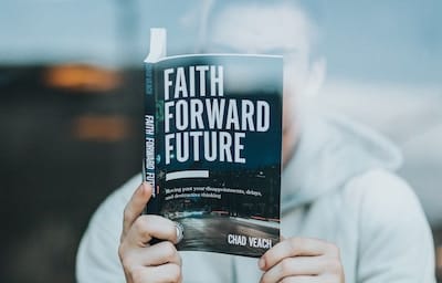 Man reading a book titled Faith Forward Future