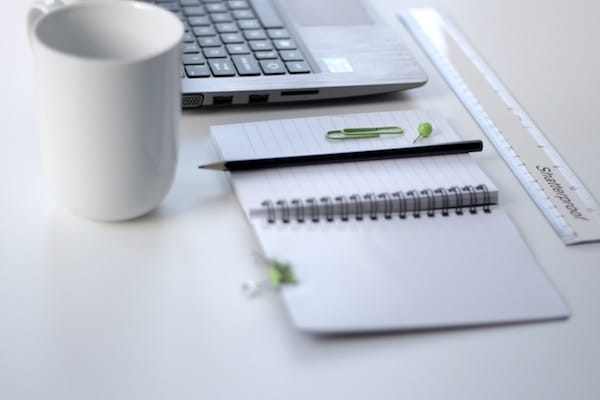 Desk with laptop, notepad, ruler, coffee mug, and pen