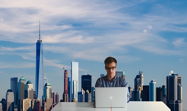 Man working on a laptop with a skyline in the background