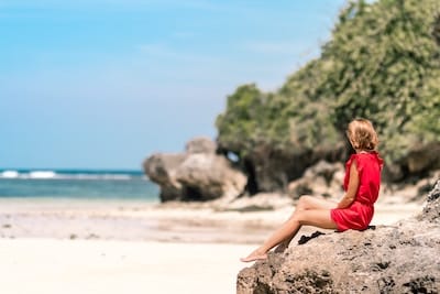 Girl sitting on rock by the ocean