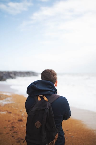 A student with a backpack looking out at the coastline