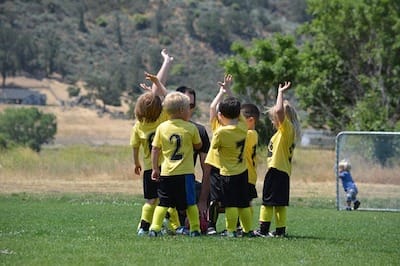 Kids soccer team high-fiving at the end of the game